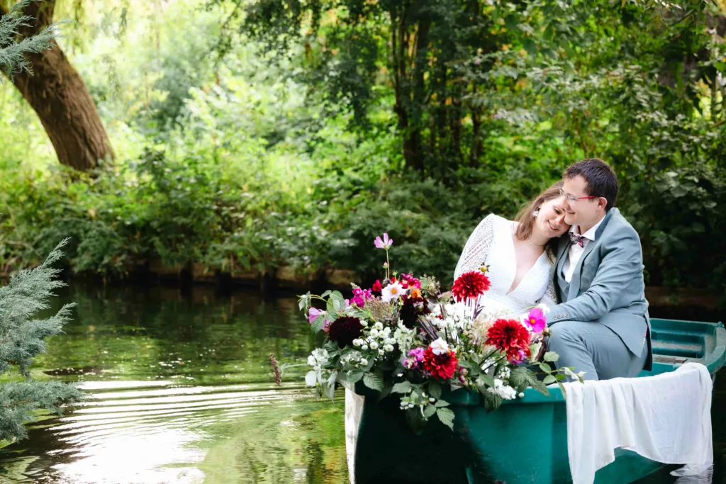 couple amoureux, séance photo couple, romance au fil de l’eau, hortillonnages Amiens, barque fleurie, fleurs colorées, photographe Amiens, expérience romantique, séance engagement, moment complice, mariés heureux, nature verdoyante, Hauts-de-France, souvenir unique, photographie naturelle, amour authentique, décoration florale, barque traditionnelle, expérience poétique, photographe couple Hauts-de-France