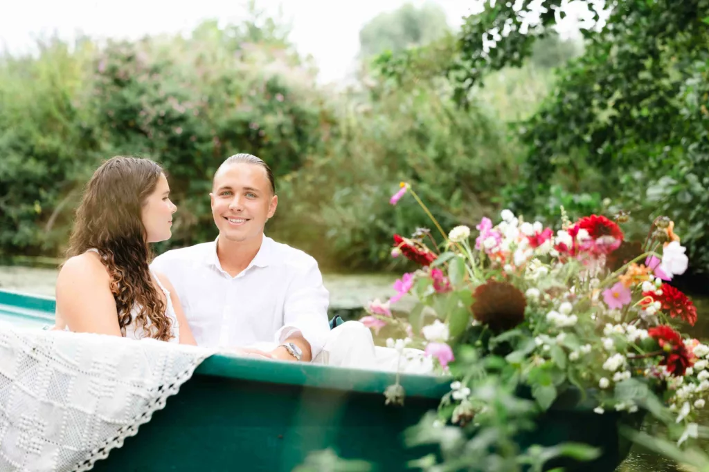 jeune homme chemise blanche, barque fleurie, hortillonnages Amiens, séance photo couple, romance au fil de l’eau, demande en mariage, photographe Amiens, expérience romantique, moment complice, fleurs colorées, amour authentique, Hauts-de-France, souvenir romantique, photographie naturelle, barque traditionnelle, expérience poétique